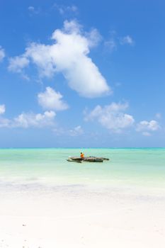 Solitary fishing boat on picture perfect white sandy beach with turquoise blue sea, Paje, Zanzibar, Tanzania. Copy space.