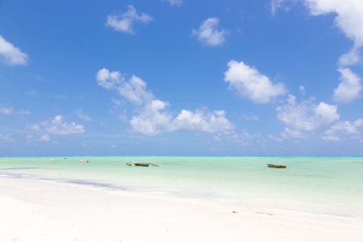 Traditional wooden fishing boats on picture perfect white sandy beach with turquoise blue sea, Paje, Zanzibar, Tanzania. Copy space.