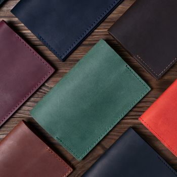Seven handmade leather passport covers on wooden textured background. Up to down view. Stock photo of luxury accessories.