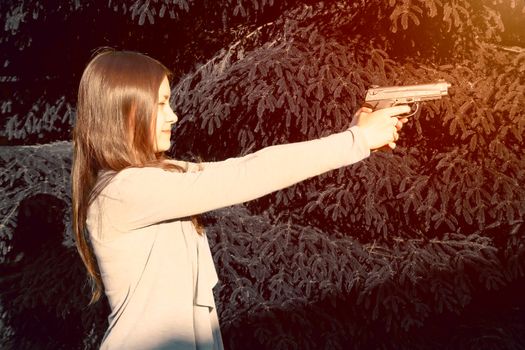 Pretty young Girl aiming from a pneumatic gun, outdoors.