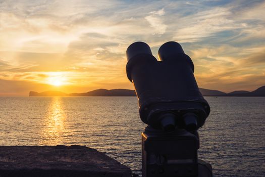 binoculars for tourists during the sunset in front of the giant that sleeps in the Gulf of Alghero, Sardinia, Italy