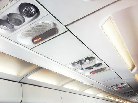 No smoking signs and controls for adjusting the air conditioning and personal lights inside a commercial aircraft. Concept of safety, transport and travel. Illuminated corridor of an airplane