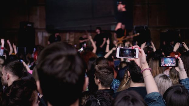 People taking photographs with touch smart phone during a music entertainment public concert. Audience At Outdoor Music Festival