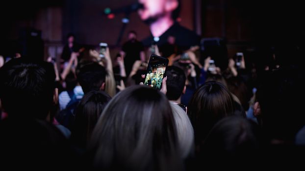 People taking photographs with touch smart phone during a music entertainment public concert. Audience At Outdoor Music Festival