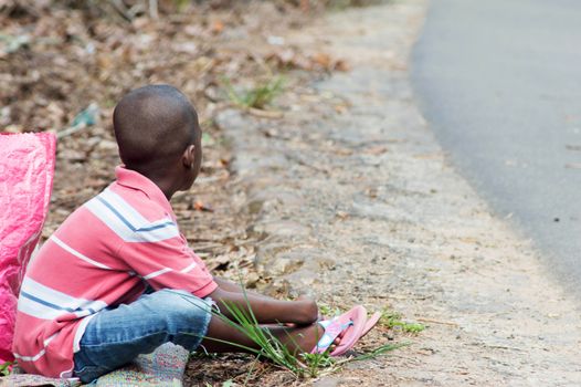a child sitting on the ground and beside him a bag.