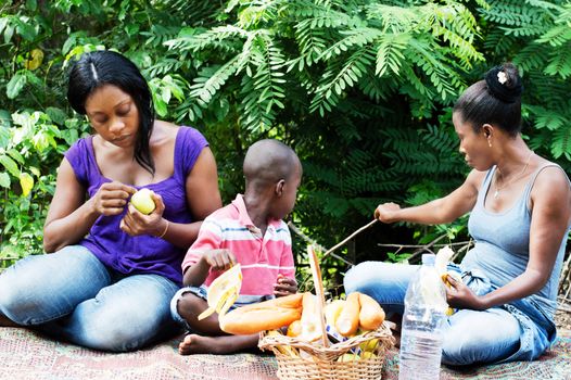 two young women sitting with a child and a basket of food before them
