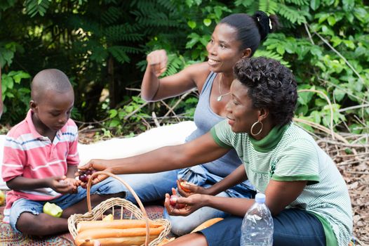 sitting on a mat, this small family camp in the countryside. And this young woman gives grapes to her son