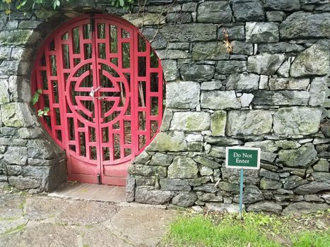 locked red door at Chinese garden with do not enter sign and stone wall