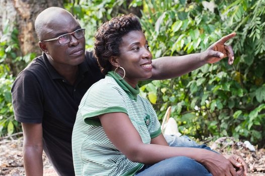 happy couple with the man pointing the finger up in the bush.