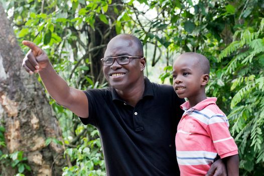 Happy father shows something to his child on a tree.