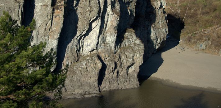 The sandy shore of the mountain river Katun with a high sheer cliff. Altai, Siberia, Russia.