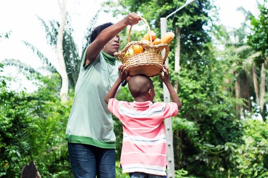 Mom puts the food basket on his son's head as he wants