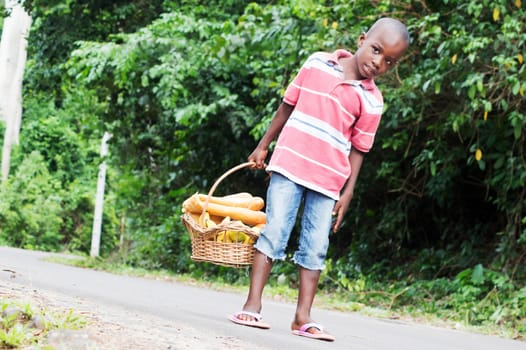 child holding a basket of food containing fruit and bread.