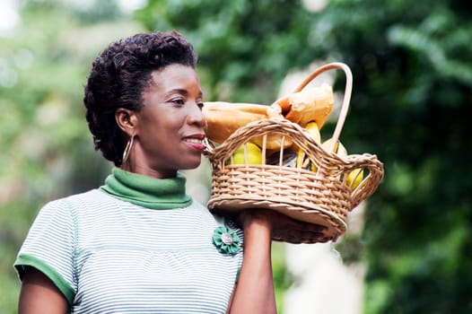 smiling young woman holding a basket of fruit in her hand and went for a picnic