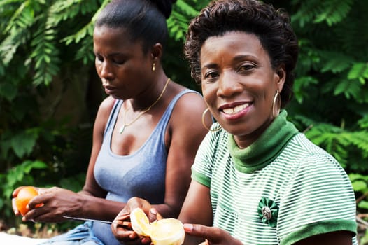 this smiling young woman is cutting an orange.