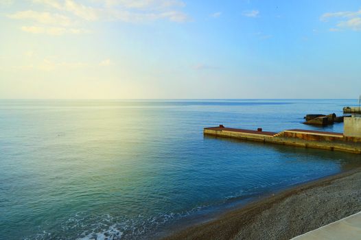 Sunrise on the sea with sun glare, pier on the shore in the early morning, calm, rest, summer holiday concept.