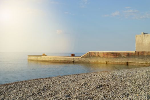 Sunrise on the sea with sun glare, pier on the shore in the early morning, calm, rest, summer holiday concept.