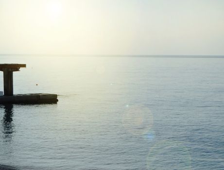 Sunrise on the sea with sun glare, pier on the shore in the early morning, calm, rest, summer holiday concept.