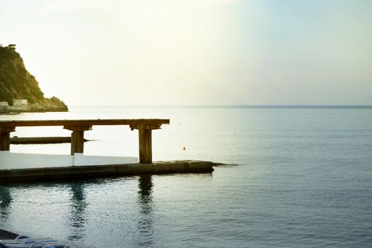 Sunrise on the sea with sun glare, pier on the shore in the early morning, calm, rest, summer holiday concept.