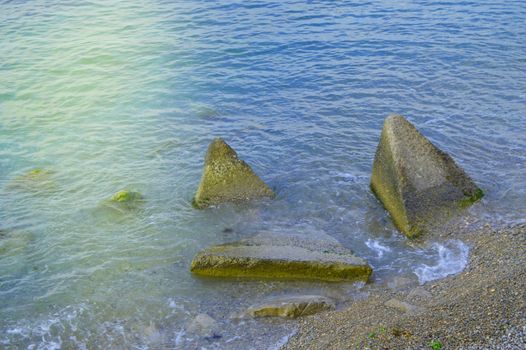 The waves of the sea beating on the huge boulders on the shore.