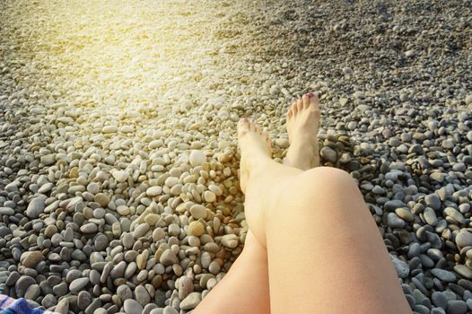 Beautiful female feet on pebbles on the beach on a Sunny summer day.