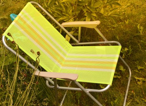 Folding chair camping is located in the garden on the grass on a Sunny summer day.