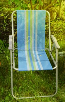 Folding chair camping is located in the garden on the grass on a Sunny summer day.