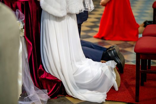 Bride and groom preparing for communion on knees at wedding ceremony in church. Bride and groom during wedding ceremony in church.