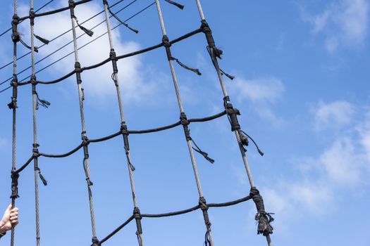 ship rigging on a blue sky background with the hand holding the line