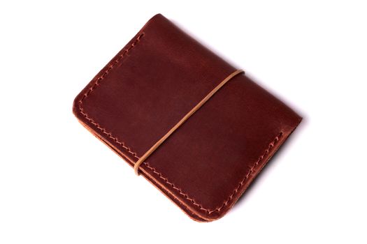 Handmade red color leather cardholder with rubber band isolated on white background closeup. Stock photo of handmade luxury accessories.