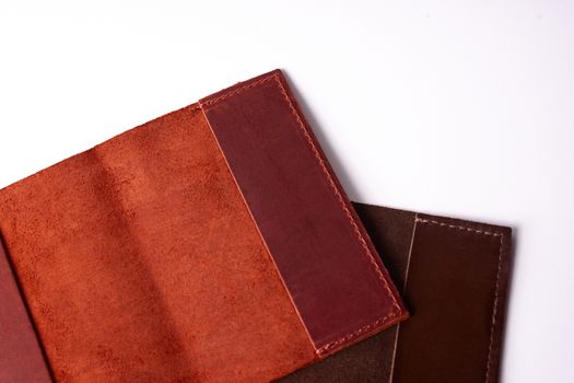 Two handmade leather passport covers isolated on white background. Closeup view. Covers are red, brown and open.