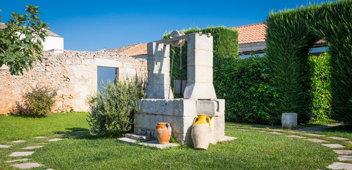 Summer season in Italy. Desing water well in an elegant garden.