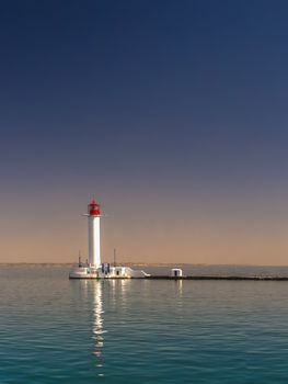 Lighthouse at the entrance to the harbor of the Odessa port, the sea gates of Ukraine in a sunny summer day