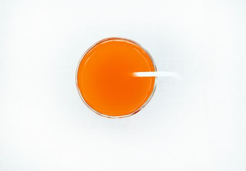 Summer drink - freshly squeezed grapefruit juice in a glass with a straw tube, top view, isolated on a white background with clipping, minimalism style.