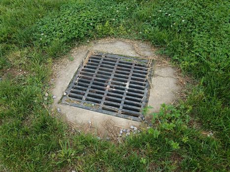 metal grate with cement and green grass or lawn outdoor