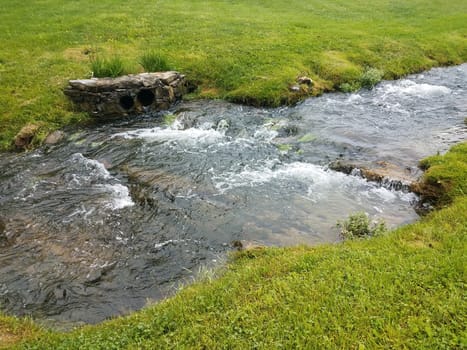 green grass or lawn with flowing river or stream or creek