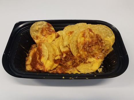 tortilla chips with cheese and meat sauce or nachos in black plastic container