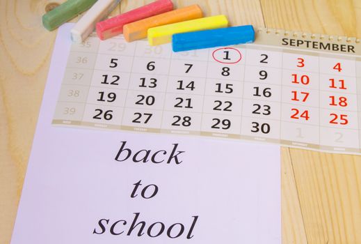 Back to school, calendar, colored chalk on wooden background.