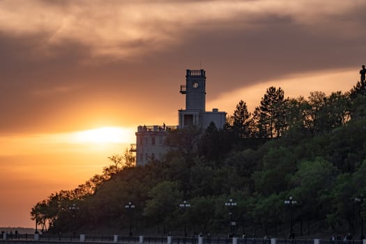 Sunset on the embankment of the Amur river in Khabarovsk. The sun set over the horizon. The embankment is lit by lanterns.