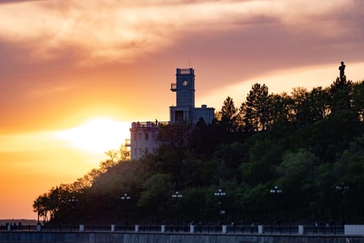 Sunset on the embankment of the Amur river in Khabarovsk. The sun set over the horizon. The embankment is lit by lanterns.