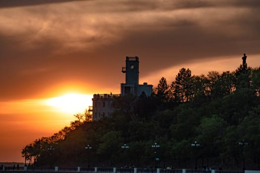 Sunset on the embankment of the Amur river in Khabarovsk. The sun set over the horizon. The embankment is lit by lanterns.