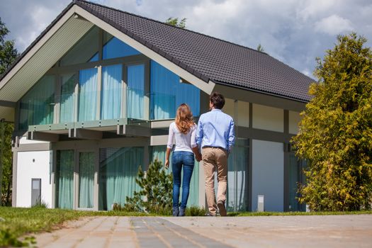 Happy couple walking outdoors near their house