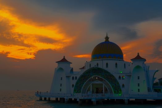 Melaka Straits Mosque at sunset by the water with orange blue grey sky