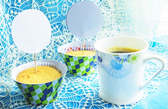 Two cupcakes on a blue napkin with lace embroidery, a Cup of coffee, the space of a card copy, the location of cards and invitations to the holiday.