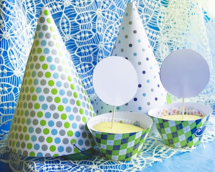 Delicious cupcakes, a party hat on a blue napkin with lace embroidery, a copy of the space map, the location of the cards and holiday invitations.