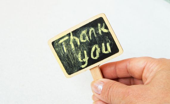 Female hand with a sign in his hands with the words thank You.