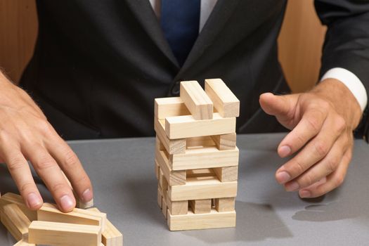 Wooden tower blocks, the hand of the businessman. Risks and planning.