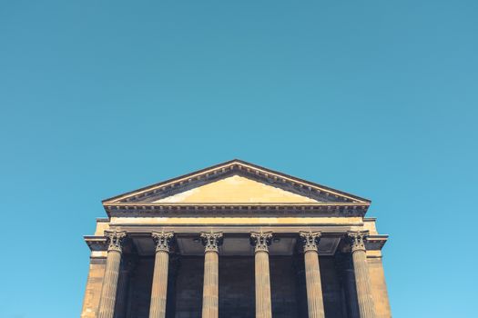 Grand Greek Or Roman Style Building With Corinthian Columns, A Bright Blue Sky And Copy Space