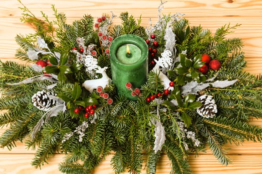 Christmas festive decoration with red baubles, holly with red berries , snow covered pine cones and winter greenery over woodpanel background.
