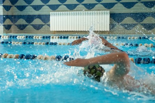 Children swimming freestyle. Indoor swimming pool with clear blue water.